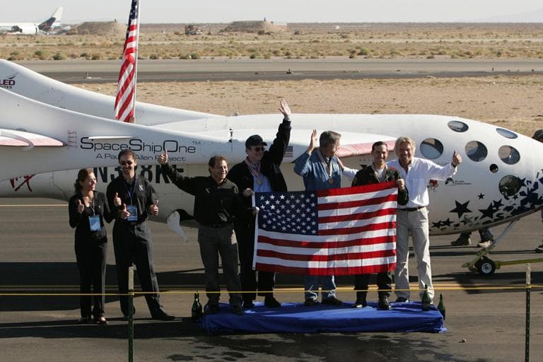 This Oct. 4, 2004 file photo shows SpaceShipOne and X Prize team members posing with a U.S. flag carried aboard the spacecraft after its successful flight into space and landing at Mojave, Calif. From left are prize sponsors Anousheh Ansari and her brother-in-law, Amir Ansari, Peter Diamandis, chairman of the Ansari X Prize Foundation, project backer Paul Allen, SpaceShipOne creator Burt Rutan, pilot Brian Binnie and Sir Richard Branson.   (AP)