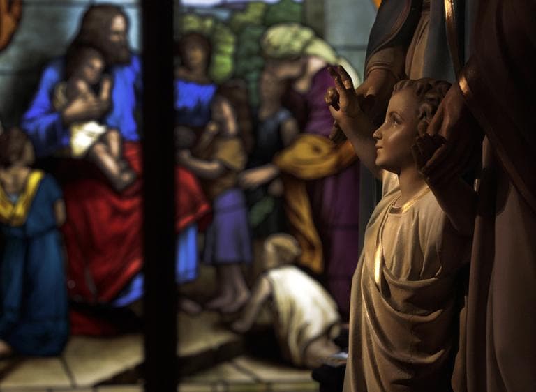 A stained glass window glows, restored and then donated to the Museum of Divine Statues, is seen beyond a statue reclaimed from St. Propcop Church of Cleveland at the museum in Lakewood, Ohio on Tuesday, Dec. 13, 2011. (AP)