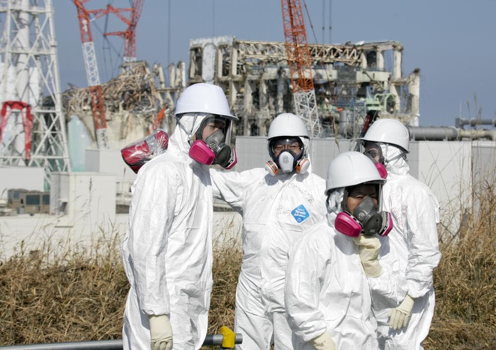 Member of the media, escorted by TEPCO employees, wearing protective suits and masks, look at the Unit 3 and Unit 4 reactor buildings of Tokyo Electric Power Co. (TEPCO)&#039;s tsunami-crippled Fukushima Daiichi nuclear power station in Okuma, Fukushima prefecture, northeastern Japan. (AP)