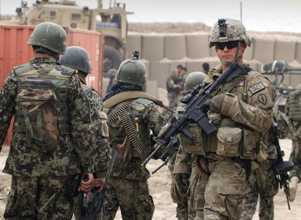Afghan soldiers, left, walk past a U.S. Army soldier outside of a military base in Panjwai, Kandahar province south of Kabul, Afghanistan, Sunday. (AP)