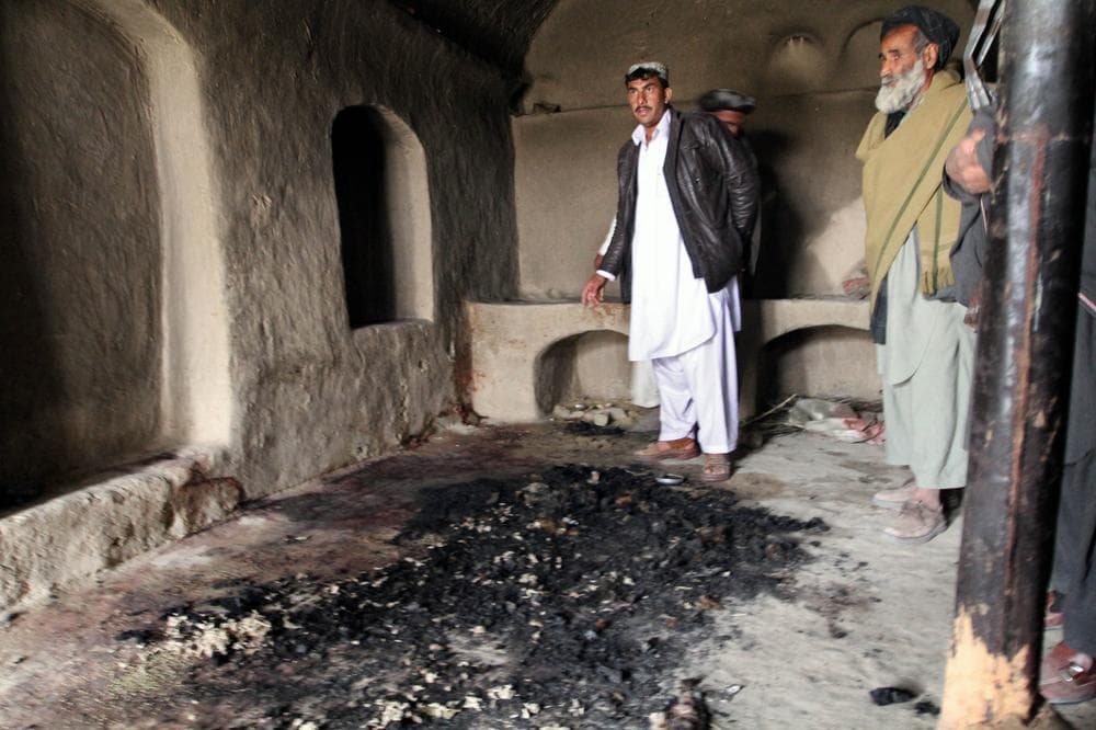 Men stand next to blood stains and charred remains inside a home where witnesses say Afghans were killed by a U.S. soldier in Panjwai, Kandahar province south of Kabul, Afghanistan, on Sunday. (AP)
