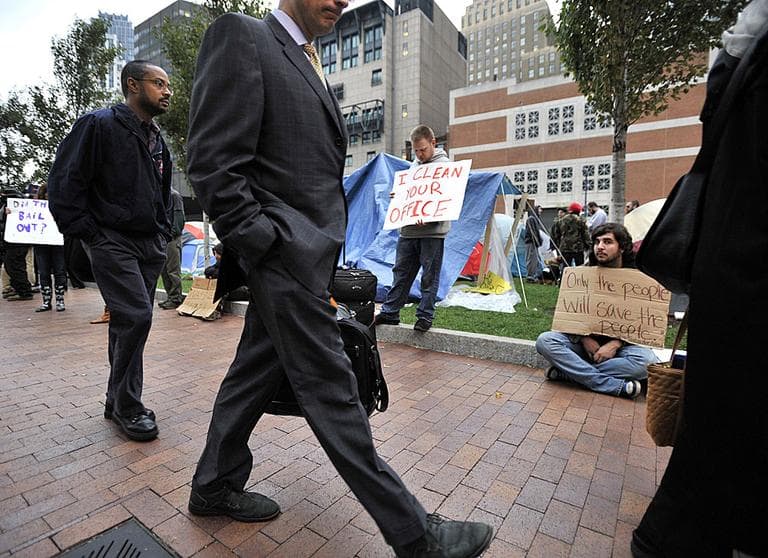 Economic inequality remains the greatest threat to the region's long-term prosperity, according to the Boston Foundation. Above, commuters walk past demonstrators with Occupy Boston in October. (AP) 