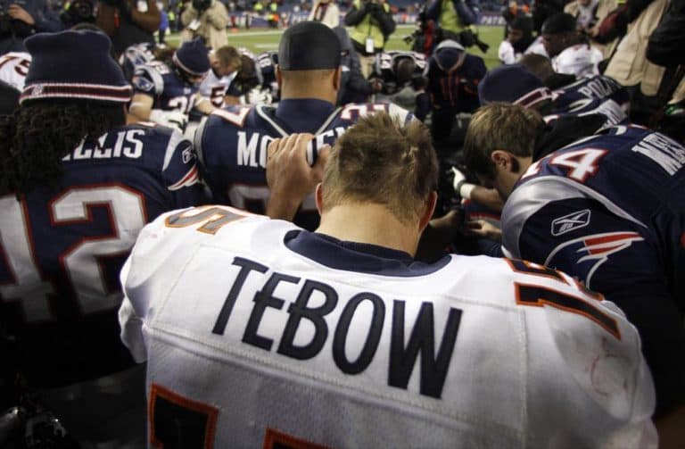 Denver Broncos quarterback Tim Tebow prays with New England Patriots and Broncos team members following an NFL divisional playoff football game Saturday, Jan. 14. (AP)
