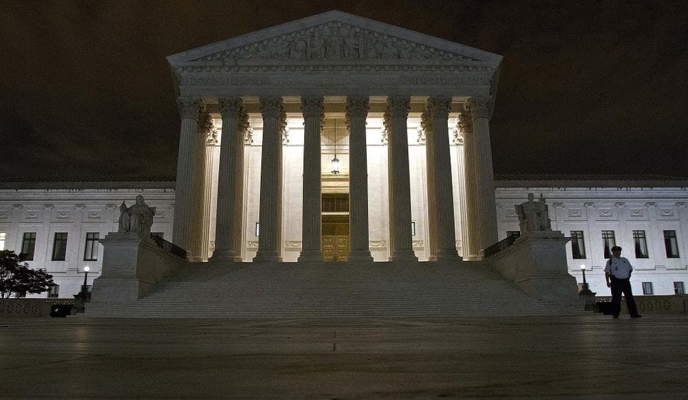 A police officer stands in front of the Supreme Court on the eve of oral arguments on President Obama's health care legislation on Sunday. (AP Photo/J. David Ake)