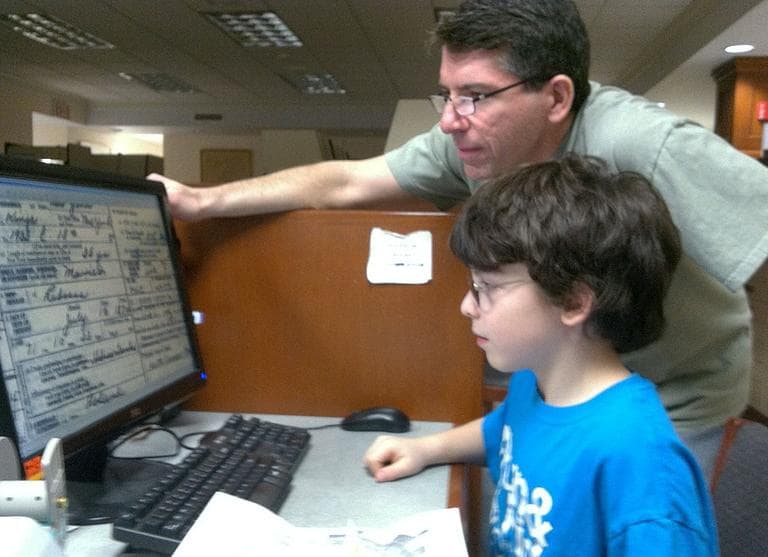Stuart Dickstein, of Cambridge, and his 9-year-old son, Zev Dickstein, search family records at the New England Historic Genealogical Society in Boston. (Steve Brown/WBUR)