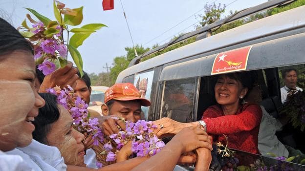 Myanmar opposition leader Aung San Suu Kyi greets supporters as she travels across the constituency where she stands as a candidate in Kawhmu on Sunday. (AFP/Getty Images)