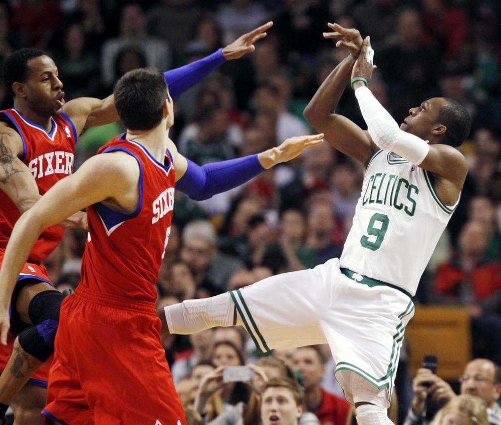 Rajon Rondo watches his 3-pointer as Philadelphia 76ers' Andre Iguodala, left and Nikola Vucevic, second from left, defend in the third quarter of  last night's home game.The Celtics won 103-79. (AP)