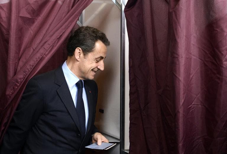 French President and UMP party candidate Nicolas Sarkozy smiles as he exits a polling booth after casting his vote in the first round of French presidential elections. (AP)