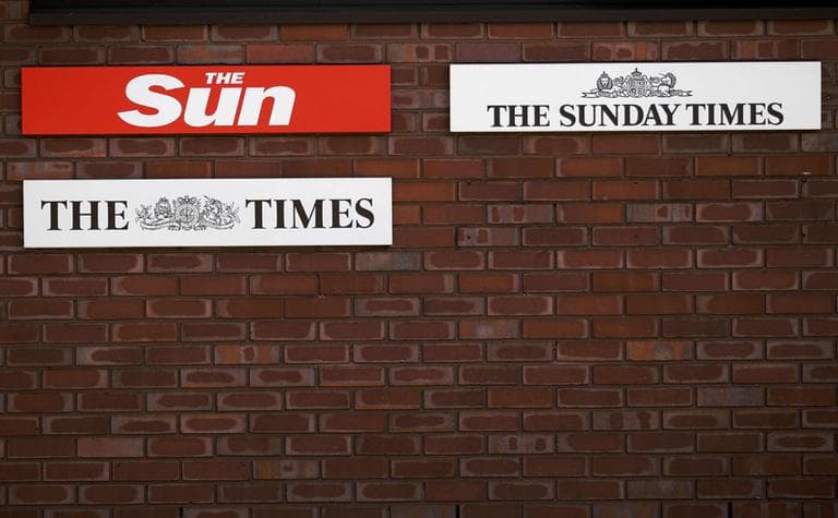 Signs showing the current News International newspaper titles are displayed where a sign for the News of the World newspaper used to sit alongside them, until its closure, outside offices of News International in London. (AP)
