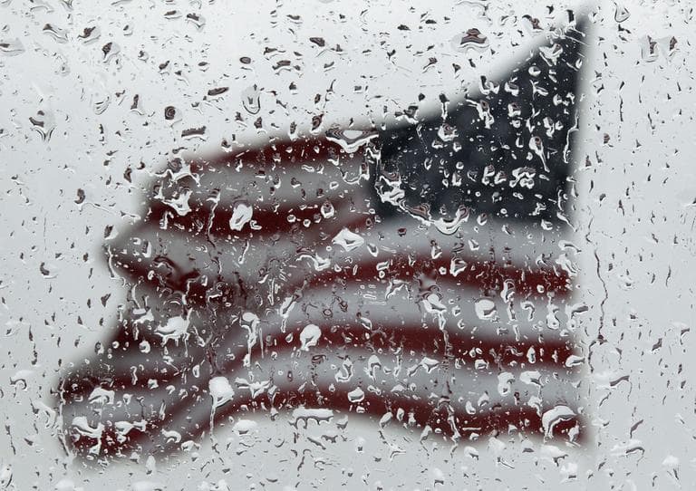 An American flag is seen through rain drops on a window as rain falls in Baltimore, Sunday, April 22, 2012. (AP)