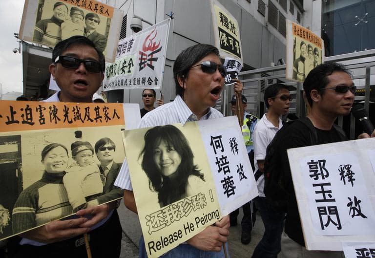 Pro-democracy protesters wearing sunglasses, hold placards with picture of blind Chinese legal activist Chen Guangcheng, third left, with his family and Chinese activist He Peirong, right, outside the China&#039;s Liaison Office in Hong Kong Monday. (AP)