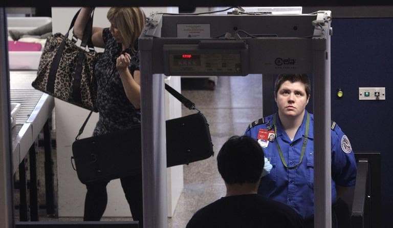 A TSA officer watches as a passenger goes through an airport metal detector. (AP)