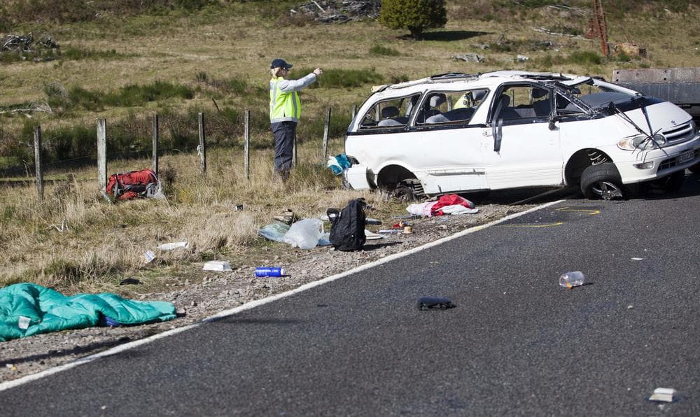 Policemen examine the scene of a minivan crash that killed three Boston University students near Turangi, New Zealand, Saturday. (AP)