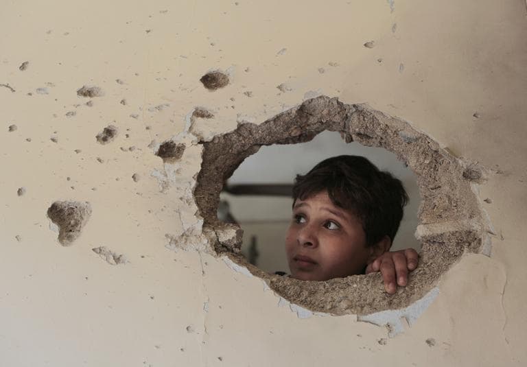 A Lebanese boy looks through a hole made by shrapnel that hit his house, after the Lebanese army deployed in the northern port city of Tripoli, Lebanon. (AP)