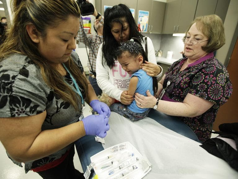 Nurses Fatima Guillen, left, and Fran Wendt, right, give Kimberly Magdeleno, 4, a Tdap whooping cough booster shot, as she is held by her mother, Claudia Solorio, at a health clinic in Tacoma, Wash. (AP)