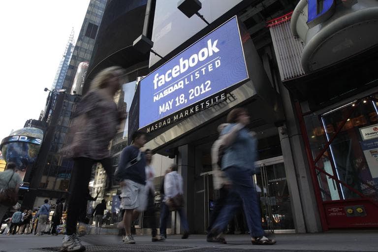 Passers-by walk near a sign for Facebook displayed at Nasdaq, Friday, May 18, in New York. (AP)