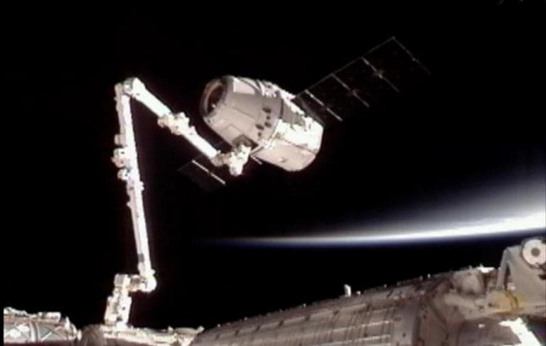 This image provided by NASA-TV shows the SpaceX Dragon commercial cargo craft, top, after Dragon was grappled by the Canadarm2 robotic arm and connected to the International Space Station on Friday. (AP/NASA)