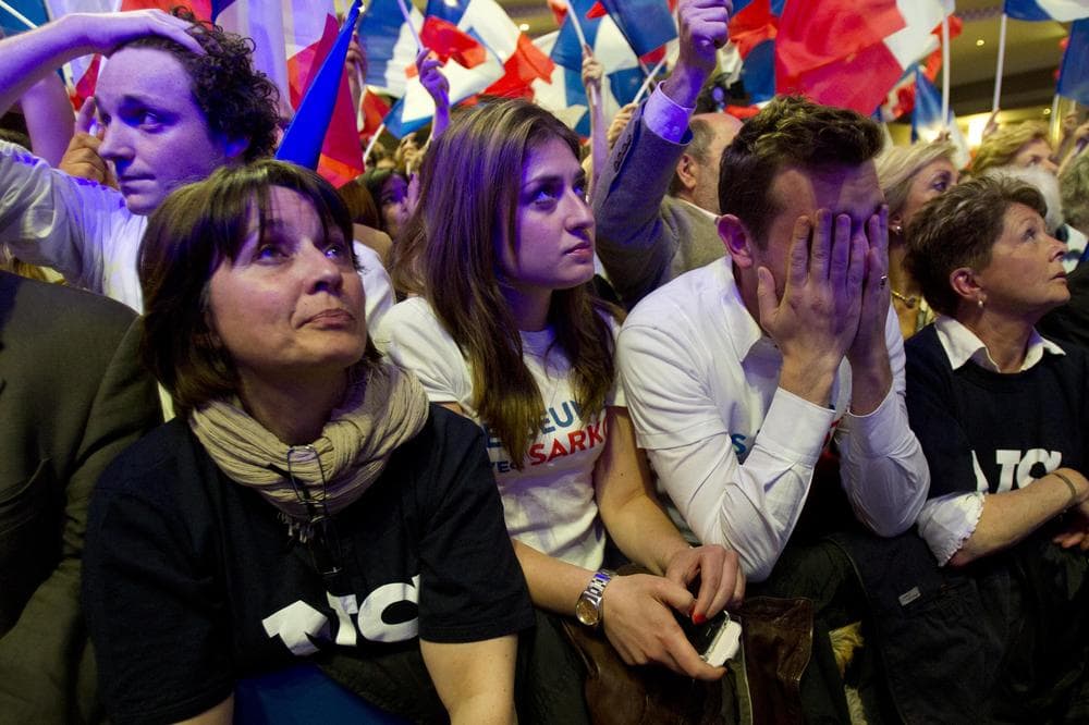 A supporters of outgoing French President Nicolas Sarkozy's Union for a Popular Movement (UMP) covers his face as the preliminary results of the second round of the presidential elections were announced at UMP headquarters in Paris Sunday May 6. The first results showed a 52 percent lead for Socialist Party candidate Francois Hollande. (AP)