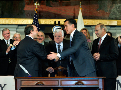 In this April 12, 2006, file photo, then-Gov. Mitt Romney is seen with lawmakers and staffers after signing the state&#039;s universal health law at Faneuil Hall in Boston. (AP File)