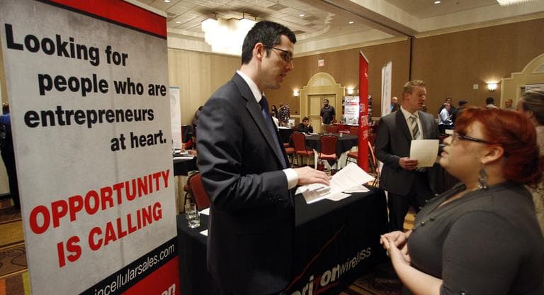 Blake Andrews with Verizon, left, visits with prospective employees during a job fair, in San Antonio. (AP)
