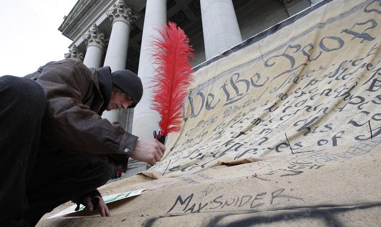 Max Snider, of Tacoma, Wash., signs his name to a giant copy of the U.S. Constitution during a protest in Olympia, Wash., Monday, Nov. 28, 2011. (AP)