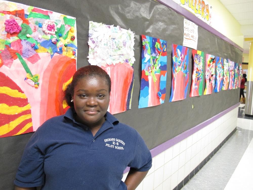 Thirteen-year-old Laiannah Victorian Butler stands near a wall of student art. Orchard Gardens will take part in the nationwide Turnaround Arts program this year. (Monica Brady-Myerov/WBUR)