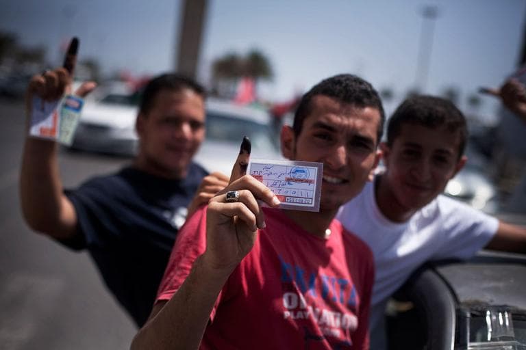Libyan men hold their elections ID cards while celebrating election day in Tripoli, Libya on Saturday, July 7. (Manu Brabo/AP)