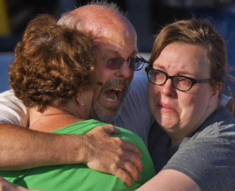 Tom Sullivan, center, embraces family members outside Gateway High School where he has been searching franticly for his son Alex Sullivan who celebrated his 27th birthday by going to see "The Dark Knight Rises," movie where a gunman opened fire Friday, in Aurora, Colo. (AP)