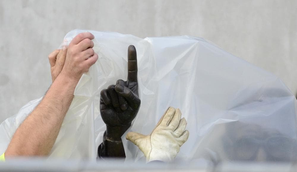Workers handle the statue of former Penn State football coach Joe Paterno before removing the statue Sunday. (AP)
