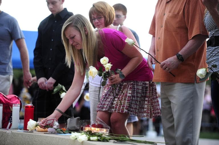 Family members of the victims of the Century 16 theater shooting leave roses at a memorial display during a vigil at the Aurora Municipal Center campus in Aurora, Colo. Sunday. (AP/The Denver Post, AAron Ontiveroz, Pool)