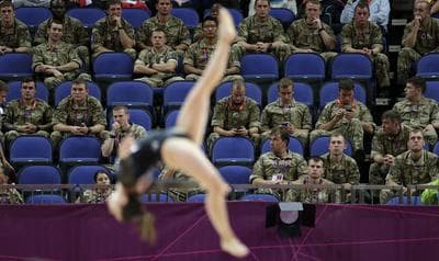 British soldiers watch gymnast Simona Castro Lazo from Chile perform during the Artistic Gymnastics women's qualification at the 2012 Summer Olympics, Sunday in London. Troops, teachers and students are getting free tickets to fill prime seats that were empty at some Olympic venues on the first full day of competition. (AP)