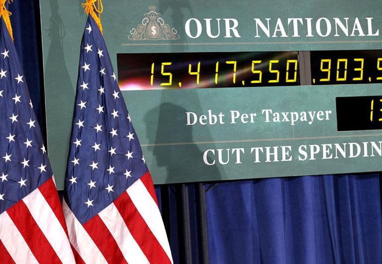 The shadow of Republican presidential candidate, former Massachusetts Gov. Mitt Romney, is seen on a representation of the National Debt Clock as he speaks at a town hall meeting in Kalamazoo, Mich., Friday, Feb. 24, 2012. (AP)