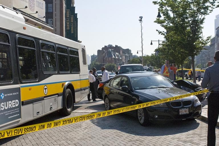 An off-duty MBTA bus hit a parking officer and pushed two vehicles into the median in Kenmore Square Thursday morning. (Josh Berlinger for WBUR)
