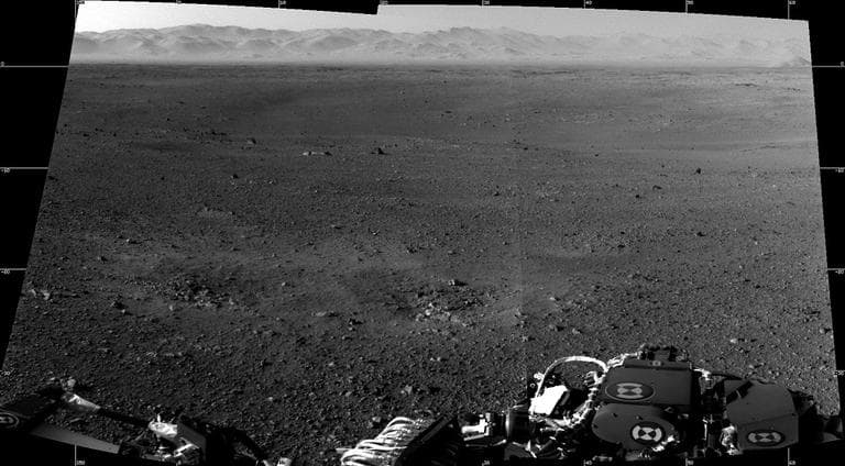 This image shows a mosaic of the first two full-resolution images of the Martian surface from the Navigation cameras on NASA's Curiosity rover. The rim of Gale Crater can be seen in the distance beyond the pebbly ground. The foreground shows two distinct zones of excavation likely carved out by blasts from the rover's descent stage thrusters. (AP Photo/NASA)