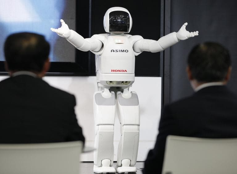 Visitors watch a Honda Asimo robot performing at the headquarters of Honda Motor Co. in Tokyo. Canon Inc. is moving toward fully automating digital camera production in an effort to cut costs. (AP)