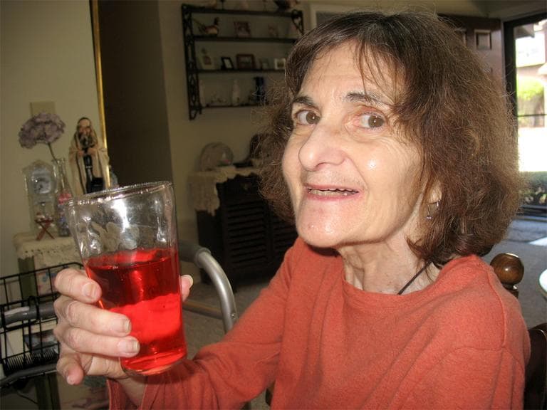 Sue Beder, with diet cranberry juice, in her Stoughton living room (Martha Bebinger/WBUR)