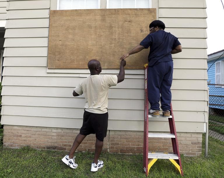 Stacey Davis, left, hands a screw to his son as they board up windows on their home before Tropical Storm Isaac hits in New Orleans. (AP)