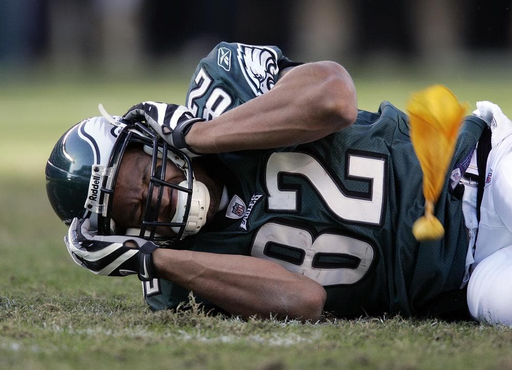 As the 2012 NFL season gets underway, commentator Bill Littlefield explores the consequences of our national obsession. In this Oct. 26, 2008 photo Philadelphia Eagles tight end L.J. Smith holds his head after a hard hit that resulted in a concussion. (AP File Photo)