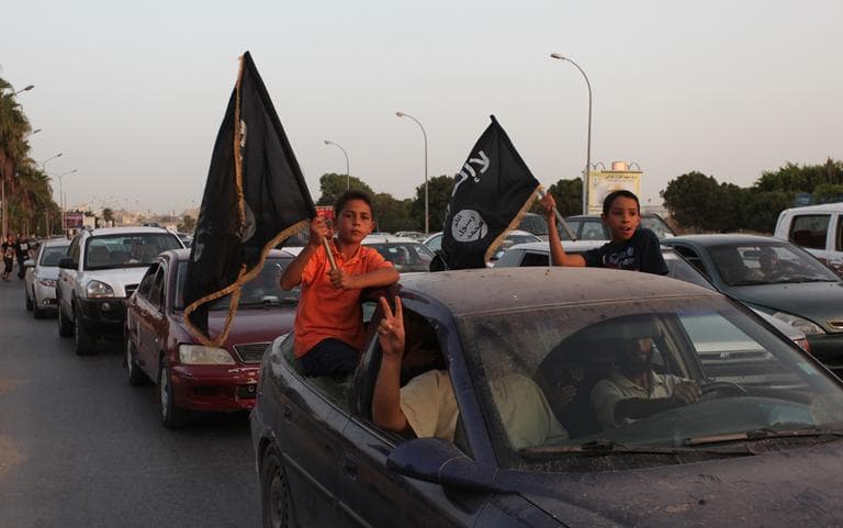 Libyan followers of Ansar al-Shariah Brigades wave black flags with Arabic writing that reads "there is no God but Allah and Muhammad is his messenger," during a protest in front of the Tibesti Hotel, in Benghazi, Libya. (AP)