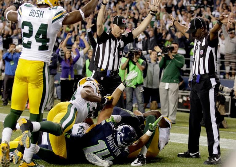 One official, left, signals a Seattle Seahawks touchdown, while the other official signals a touchback for the Green Bay Packers, Monday night in Seattle. (AP)
