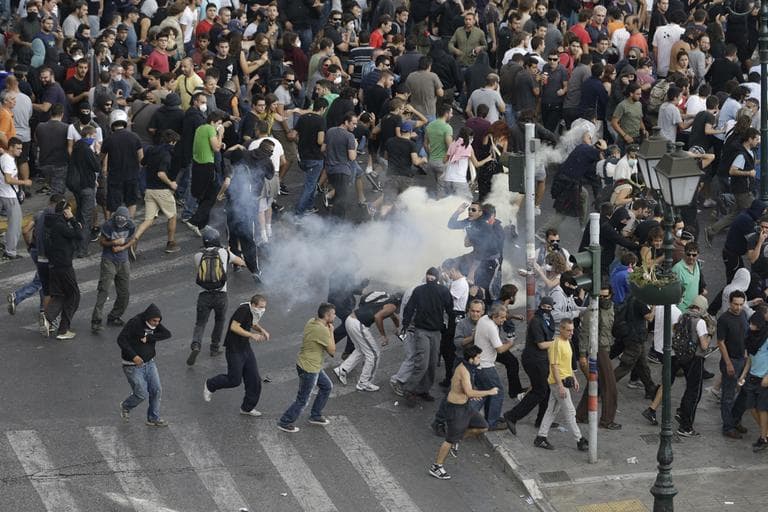 Protestors run away from tear gas during clashes in front of the parliament in Athens on Tuesday. German chancellor Angela Merkel says Greece has covered "much of the ground" required for recovery, during her landmark visit to the financially stricken country. (AP/Dimitri Messinis)