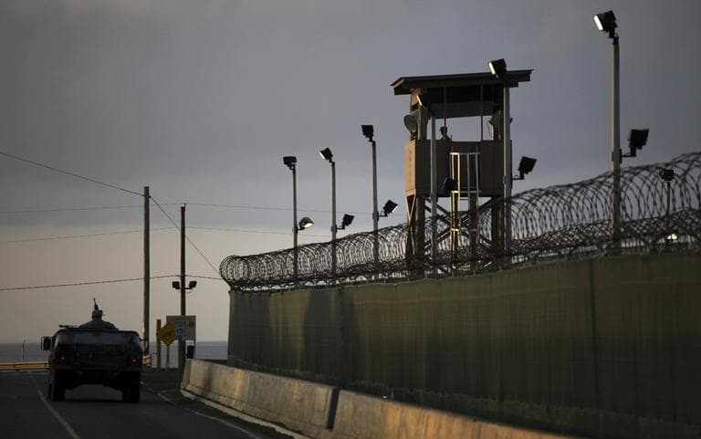 A U.S. trooper stands in the turret of a vehicle with a machine gun, left, as a guard looks out from a tower, in this 2010 photo of Guantanamo Bay U.S. Naval Base in Cuba. (AP/Brennan Linsley)