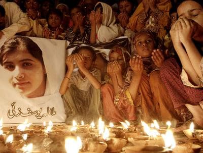 Pakistani children pray for the recovery of 14-year-old schoolgirl Malala Yousufzai, who was shot on Tuesday by the Taliban for speaking out in support of education for women, during a candlelight vigil in Karachi, Pakistan, Friday, Oct. 12, 2012. A Pakistani military spokesman says Yousufzai is in &quot;satisfactory&quot; condition but cautions that the next few days will be critical. Writing reads on the poster left, &quot;Malala Yousufzai.&quot;(AP)