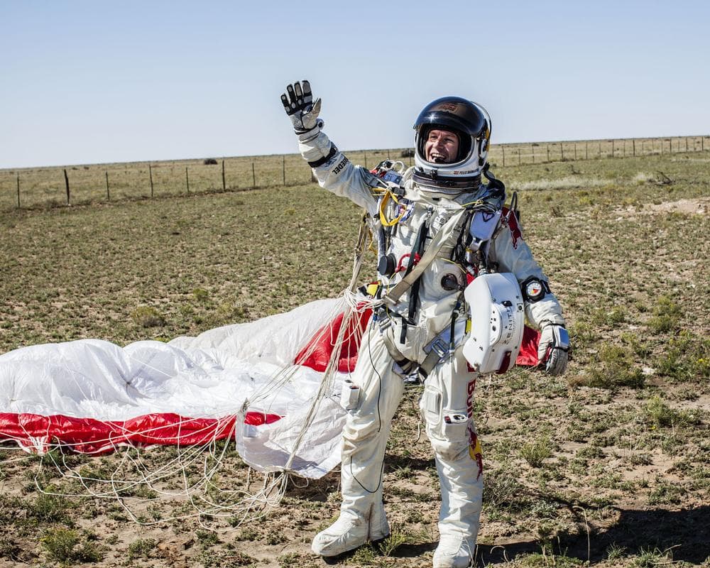 Felix Baumgartner celebrates his safe landing in the eastern New Mexico desert about nine minutes after jumping from his capsule at 128,097 feet, or roughly 24 miles, above Earth on Sunday. (Balazs Gardi/AP/Red Bull Stratos/)