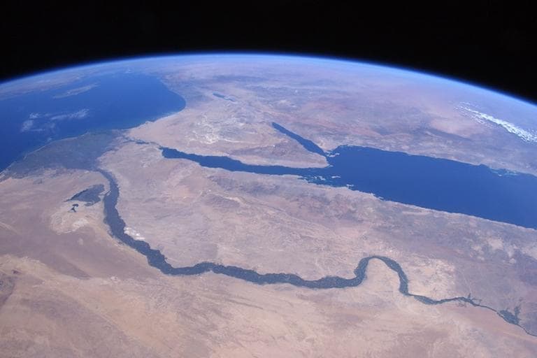 Over the Sahara Desert approaching ancient lands and thousands of years of history. The Nile River flowing through Egypt past the pyramids of Giza up to Cairo in the delta; the Red Sea, Sinai Peninsula, Dead Sea; Jordan River; and the Sea of Galilee are visible, as are the island of Cyprus in the Mediterranean Sea and Greece coming over the horizon. (NASA)