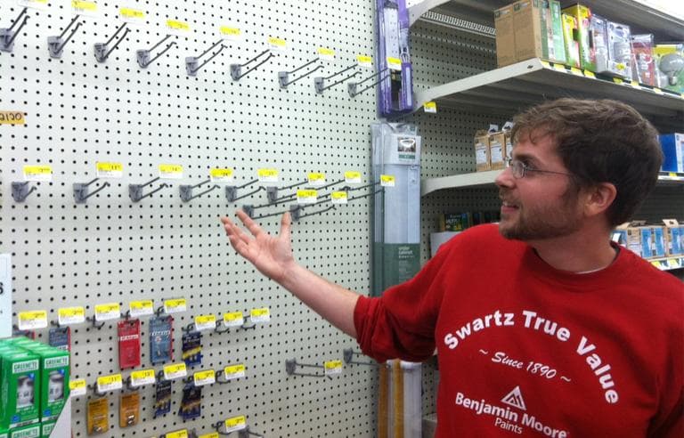 Salesperson Jeremy Perry, 27, shows the now-empty flashlight section at Swartz Hardware in Newton Monday. (Andrea Shea/WBUR)
