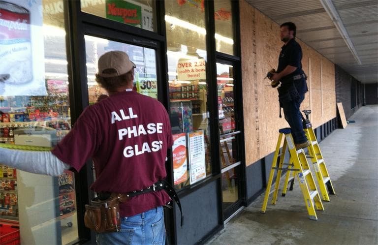 Barry Higginbottom, left, and Ryan Snyder board up a Family Dollar store near the Clark's Cove neighborhood in New Bedford on Monday. (Steve Brown/WBUR)