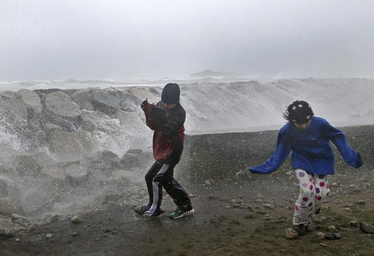 Youngsters run as waves crash against a seawall in Scituate on Monday. (Elise Amendola/AP)