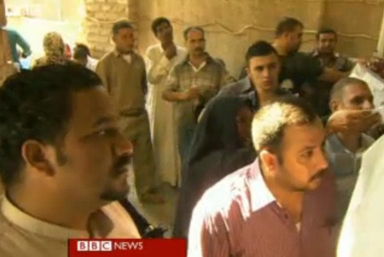Iraqis who fled to Syria are now returning to Iraq to escape the bloodshed. In this screenshot from a BBC video, Iraqis line up for government grants. (BBC screenshot)