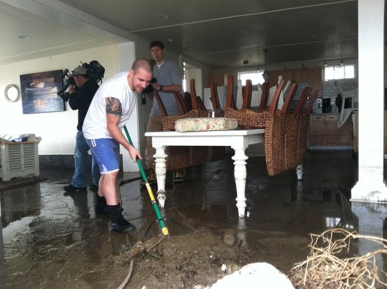 Jason Locke sweeps mud from his parents' home in Westport. (Fred Thys/WBUR)